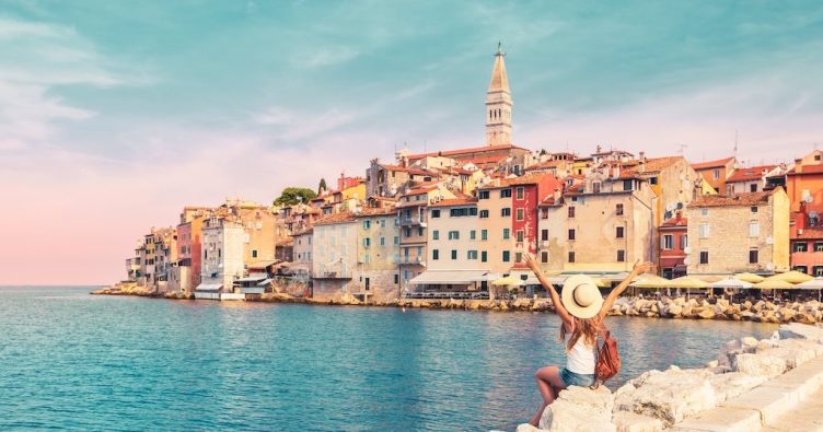 Rovinj - Frau im Sonnenuntergang mit Blick auf die Stadt und Meer bei Reise und Urlaubsziele